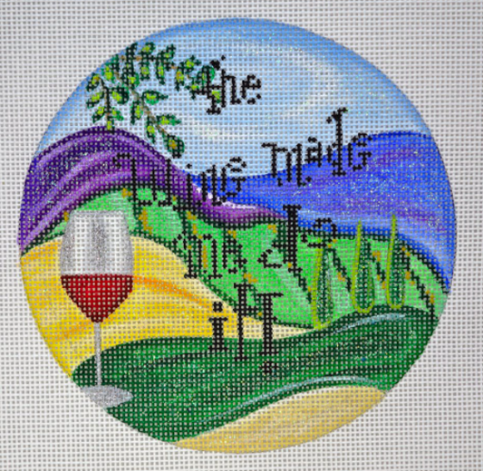 Funda Scully round needlepoint canvas of a vineyard landscape with a glass of wine and the phrase "the wine made me do it!"