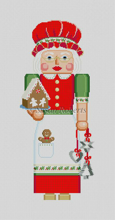 Susan Roberts needlepoint canvas of a Mrs. Claus nutcracker holding a gingerbread house and cookie cutters wearing an apron