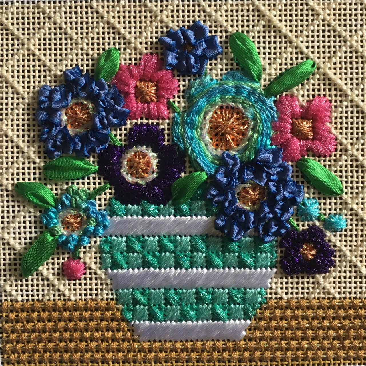 Stitched example of the Amanda Lawford blue mod flowers needlepoint canvas for a coaster with a turquoise and white vase