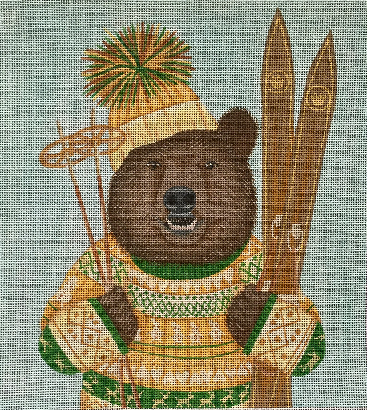 Fab Funky whimsical needlepoint canvas of a brown bear wearing a fair isle sweater and a pom pom beanie hat holding skis and ski poles