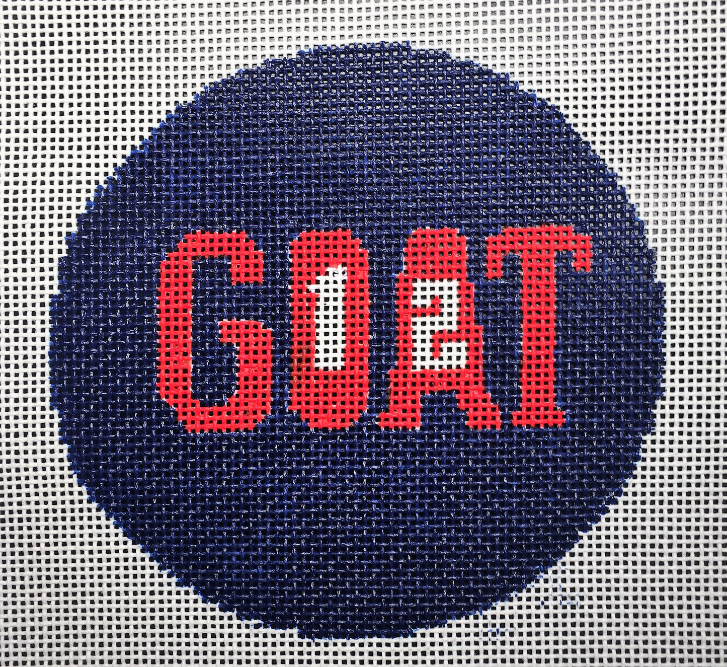 Vallerie Needlepoint Gallery round New England Patriots football teamneedlepoint canvas that says "goat" (greatest of all time) with the number 12 inset for quarterback Tom Brady