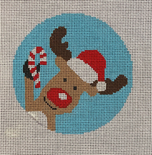 Suzie Vallerie for Vallerie Needlepoint Gallery round Christmas ornament needlepoint canvas of a whimsical Rudolph the red-nosed reindeer holding a candy cane and wearing a Santa hat