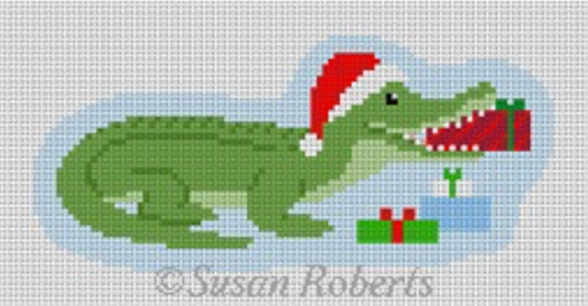 Susan Roberts ornament-sized needlepoint canvas of an alligator with Christmas presents in front of him and a present in his mouth. The alligator is wearing a Santa hat.