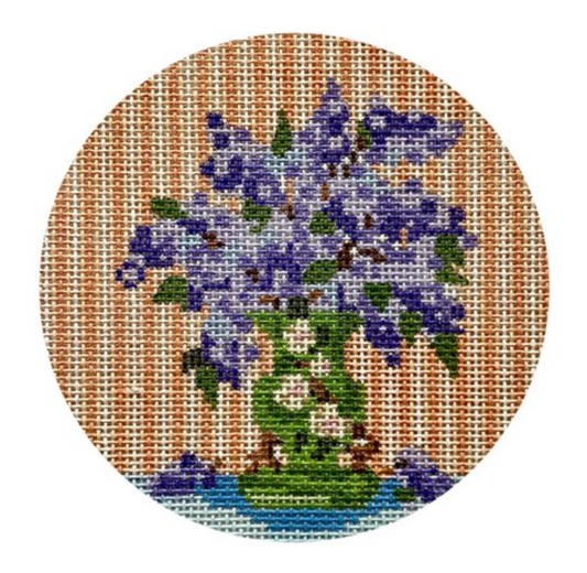 The Stitching Garden for Plum Stitchery round needlepoint canvas of lilac flowers in a green vase with peach-striped wallpaper in the background
