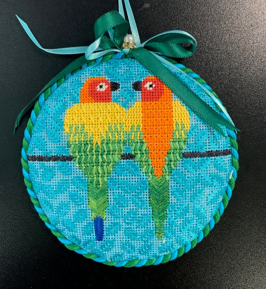 Scott Partridge round needlepoint canvas of two tropical geometric and stylized rainbow parrots sitting on a wire