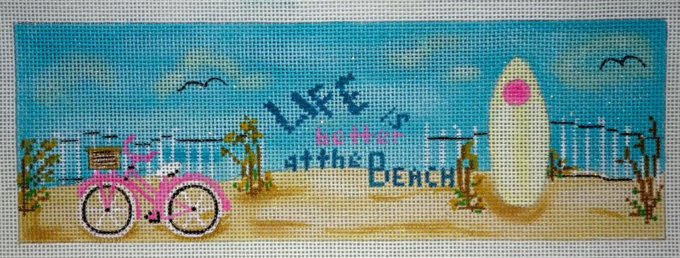 Funda Scully needlepoint canvas of a beach scene with the phrase "life is better at the beach" with a surfboard and a pink bicycle - perfect for a beach house