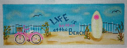 Funda Scully needlepoint canvas of a beach scene with the phrase "life is better at the beach" with a surfboard and a pink bicycle - perfect for a beach house