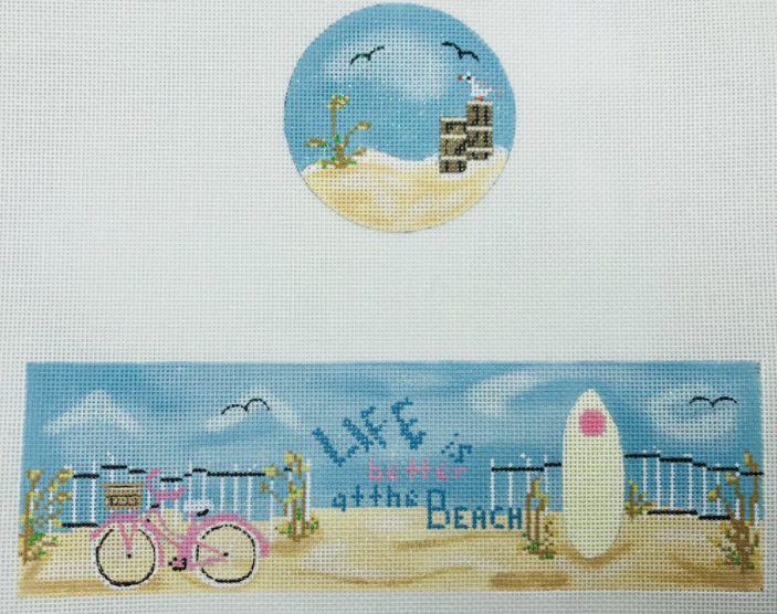 Funda Scully needlepoint canvas for a round hinged box of a beach scene that says "life is better at the beach" with a surf board and a pink bicycle