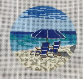 KCN Designers round needlepoint canvas of two blue beach chairs in the sand with a matching blue umbrella and the ocean in the background